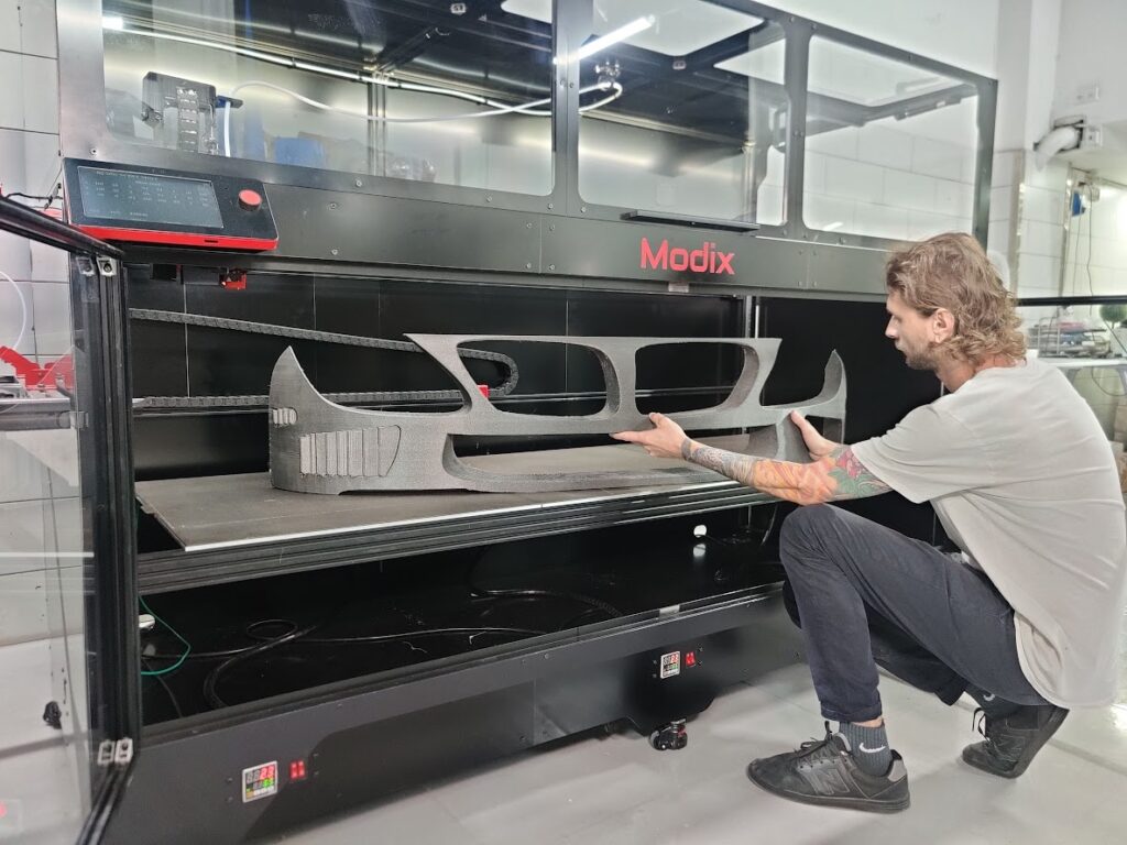 Imprimante 3D Modix BIG-180X avec une grande pièce imprimée en une seule fois, illustrant sa capacité de fabrication de pièces longues jusqu'à 1,80 m.
